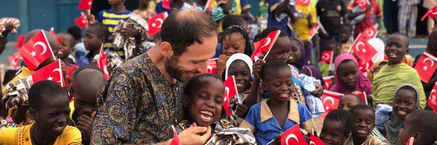 Bilal Erkuş, Afrika sahasında çocuklarla birlikte yeşil bir doğa ortamında umut ve tebessümü paylaşırken